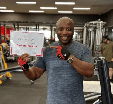 Carlton Treasure holding up a certificate in the gym