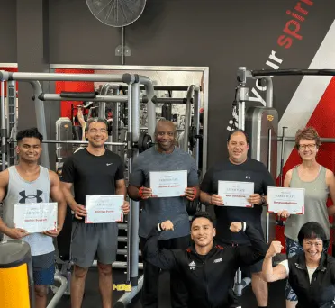 A group of Glutrition clients holding certificates in the gym