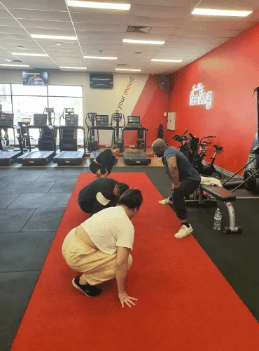 Glutrition clients stretching on the red turf strip at the gym